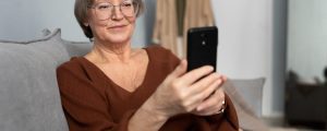 mulher-senior-feliz-usando-smartphone-na-sala-de-um-apartamento-moderno (1)